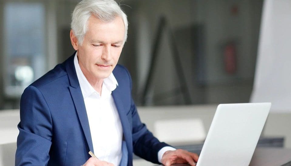 A man in a suit and tie using a laptop.