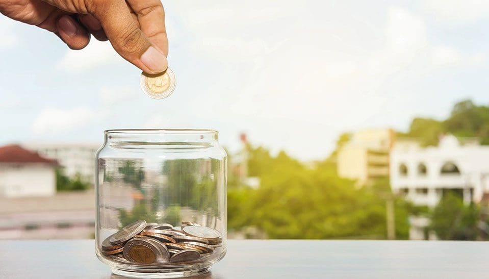 A person is putting money in a jar