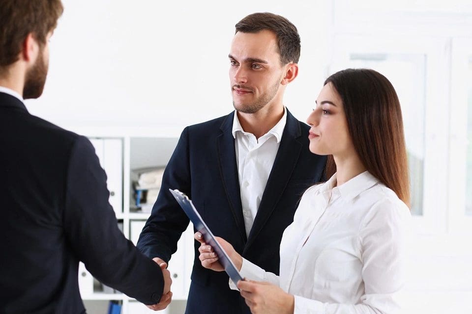 A man and woman shaking hands in front of two other people.