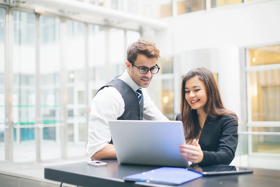 A man and woman looking at a laptop.